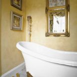 Ściany łazienki pomalowano na kolor starego złota farbami od słynnej projektantki Laury Ashley.