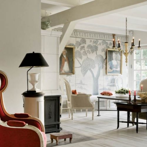 W przestronnym salonie dominują jasne, rozbielone kolory. Kontrastem są czarne stoliki i lampka, oraz czerwony fotel.